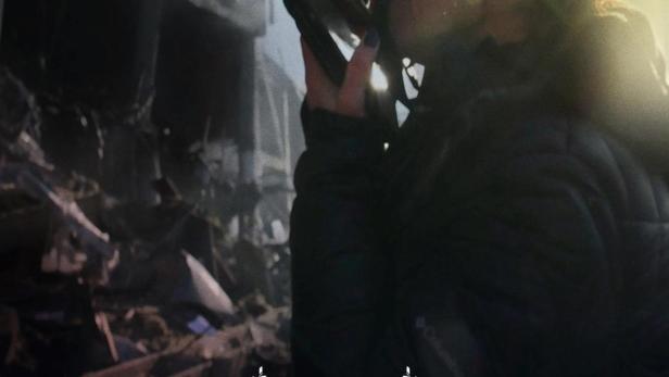 Eine Fotografin macht Aufnahmen von zerstörten Gebäuden, vermutlich für den Film „Love + War“.