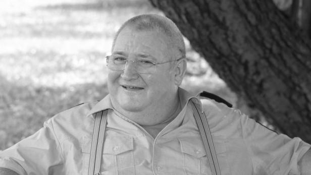 Schauspieler Horst Krause in Hemd und Hosenträgern neben einem Baum.