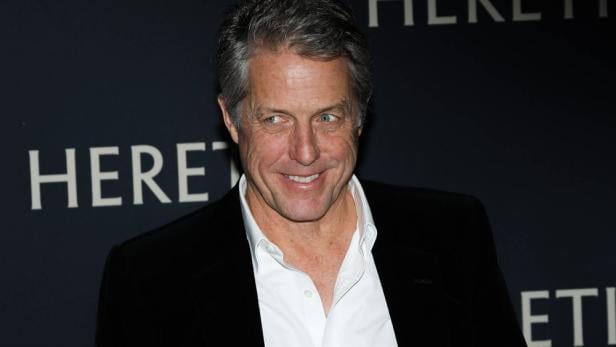 Schauspielstar Hugh Grant breit lächelnd bei Fototermin.
