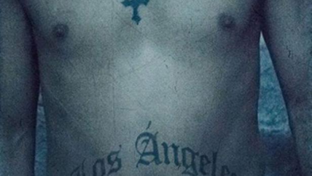 Ein Mann mit Tätowierungen und einer Pistole im Hosenbund.