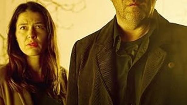 Ein Mann und eine Frau blicken besorgt, im Hintergrund das Logo des ZDF.