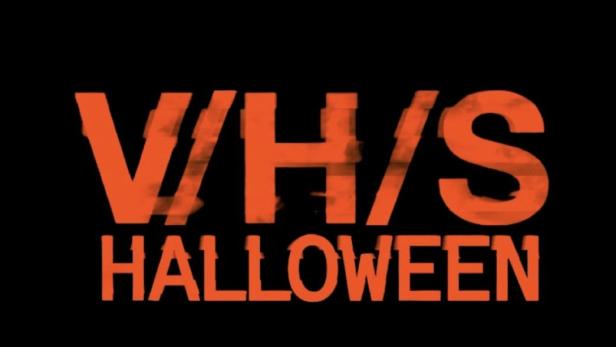 Das Cover des Films „V/H/S: Halloween“ in orangefarbener Schrift auf schwarzem Hintergrund.