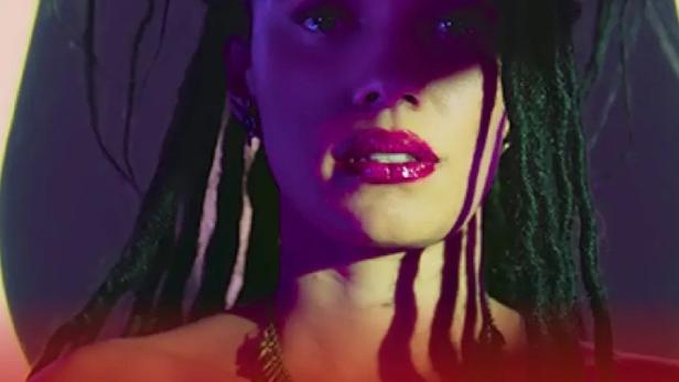 Eine Frau mit Dreadlocks und dunklem Hut, im Vordergrund der Titel „Love Kills“.