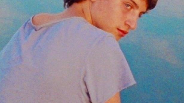 Ein junger Mann blickt auf dem Filmplakat zu „Estrany riu“ über seine Schulter.