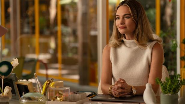 Lily James sitzt als Selfmade-Milliardärin Whitney Wolfe an einem Bürotisch.