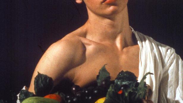 Ein junger Mann hält einen Korb mit Obst und Gemüse.