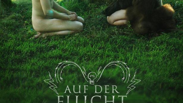 Zwei Personen mit Tierkopfmasken sitzen sich auf einer Wiese gegenüber.