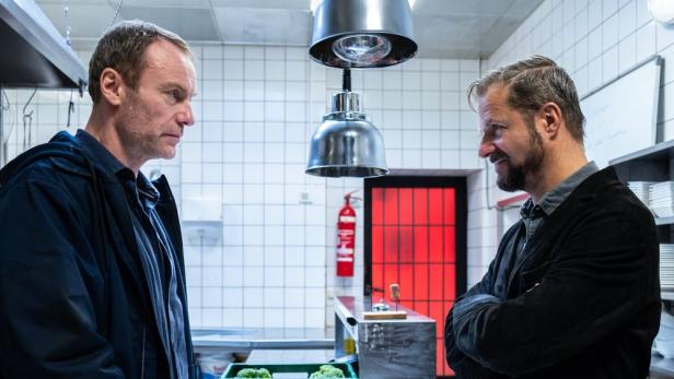 Zwei Männer stehen einander in einer Restaurantküche gegenüber.