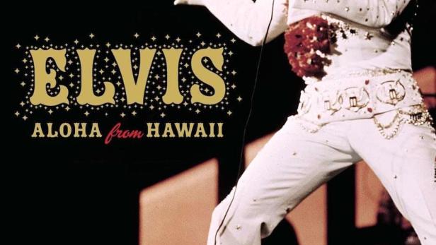 Elvis Presley tritt in seinem weißen „Aloha from Hawaii“-Anzug auf einer Bühne auf.
