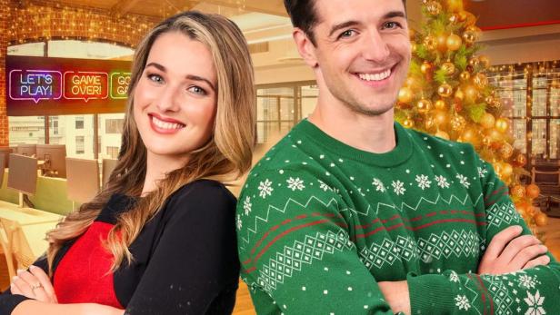 Ein Mann und eine Frau stehen vor dem Filmplakat „Der Geist der Weihnacht“.