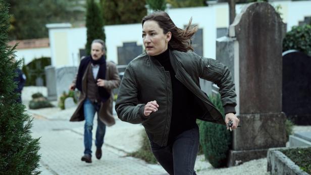 Michael Ostrowski und Marie Leuenberger laufen über einen Friedhof.