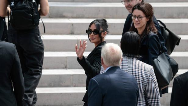 Kim Kardashian in Menschenmenge winkt Fotografen von einer Treppe aus zu 
