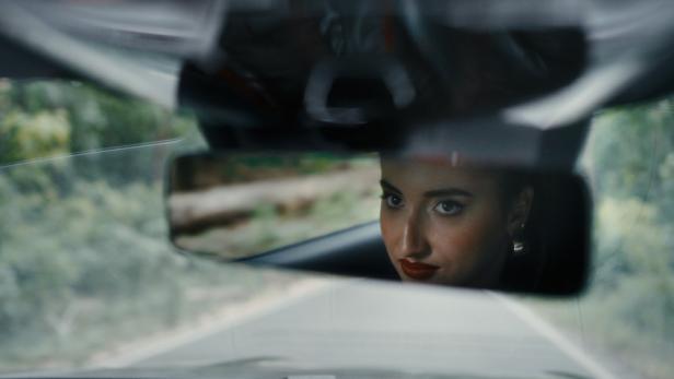 Gesicht einer Frau während der Fahrt im Rückspiegel eines Autos zu sehen