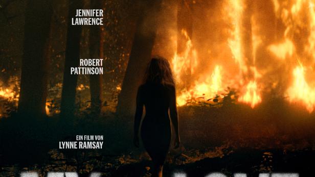 Frau geht nachts auf brennenden Wald zu