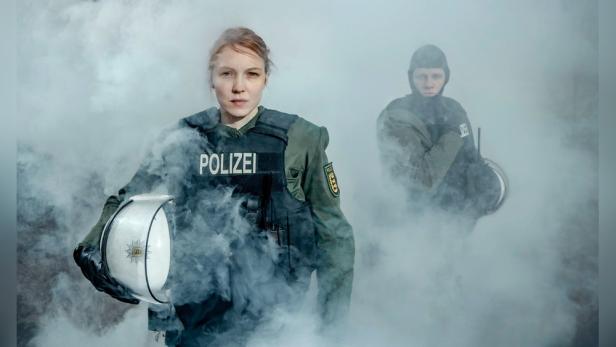 Frau in Polizeiuniform von Rauchgasschwaden umhüllt