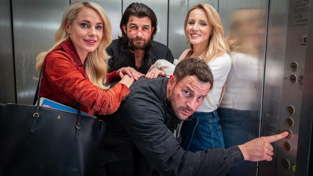 Zwei Frauen und zwei Männer in einer Aufzugskabine