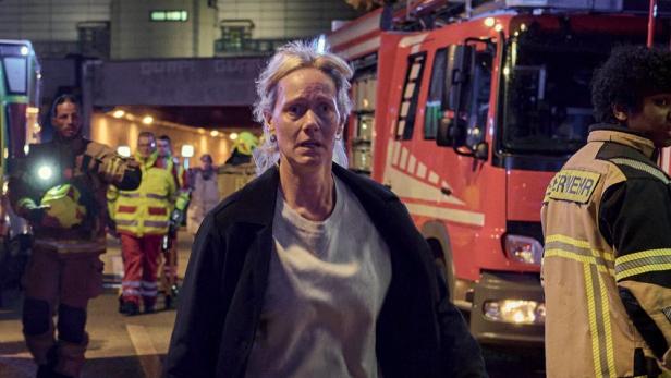 Frau steht neben Feuerwehrauto bei einem Unfalleinsatz