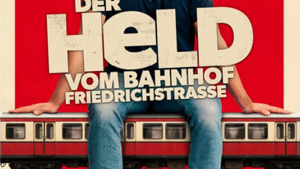 Charly Hübner sitzt auf einem Straßenbahnwagen