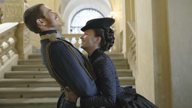 Frau fasst auf einer Treppe  Mann in Uniform um die Taille