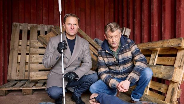 Zwei Männer kauern auf dem Boden in einem Lagerraum