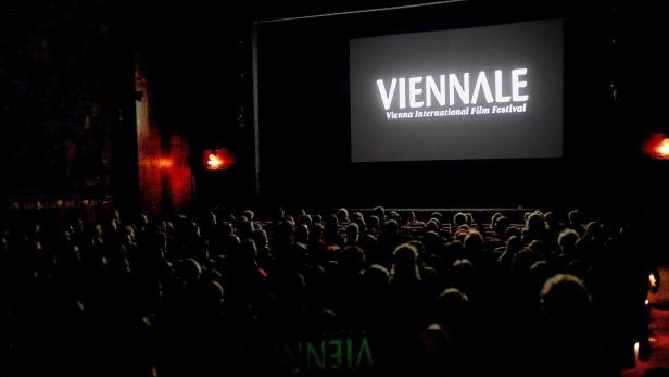 In einem vollbesetzten dunklen Kino ist der "Viennale"-Schriftzug auf der Leinwand zu sehen