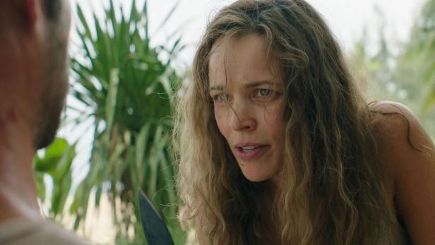 Frau kauert auf Palmeninsel vor einem Mann