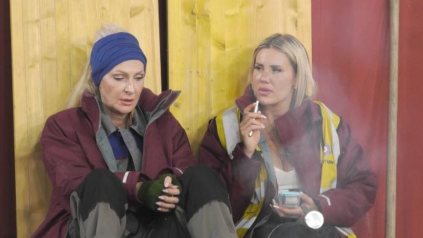 Zwei Frauen, von denen die eine raucht, sitzen nebeneinander