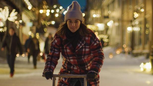 Junge Frau abends in einer weihnachtlich geschmückten Einkaufsstraße