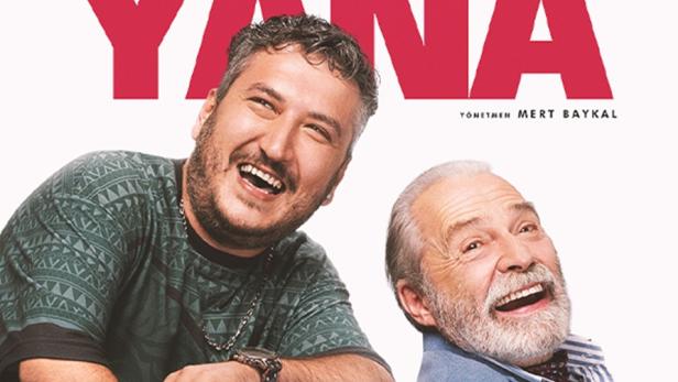 Jüngerer Mann lehnt sich auf die Rückenlehne eines Rollstuhles, in dem ein älterer Mann sitzt