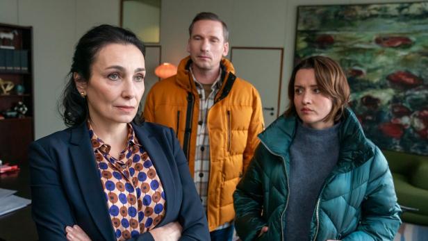 Zwei Frauen und ein Mann stehen in einem Brüo zusammen