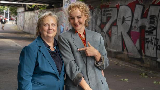 Zwei Frauen in einer offenen Unterführung, deren Wände mit Graffiti bedeckt sind