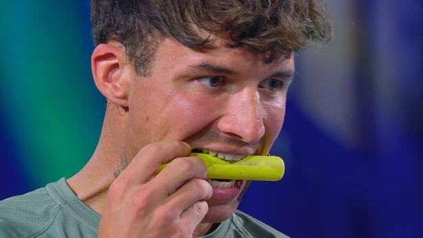 Micha nimmt ein grünes Plastikteil zwischen die Zähne