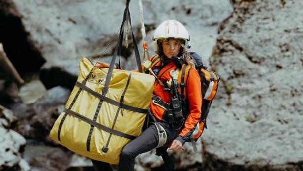 Frau bei Tauflug am Hubschrauber im Gebirge