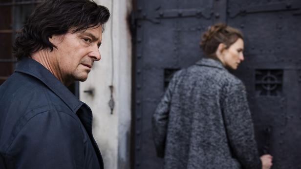 Mann steht hinter Frau vor einem großen Tor aus Metall