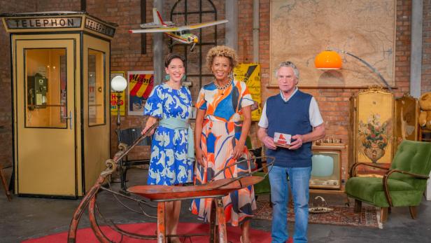 Arabella Kiesbauer steht im Studio vor einem historischen Gasslschlitten