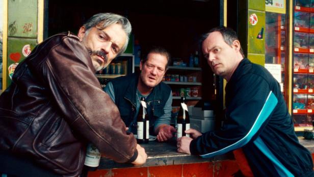 Drei Männer stehen mit Bierflaschen an einer Theke