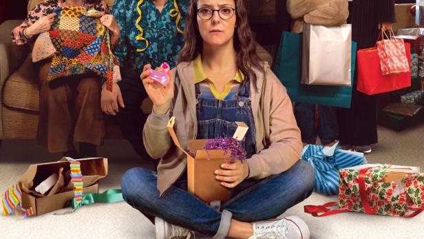 Familie mit teils ausgepackten Weihnachtsgeschenken im Wohnzimmer