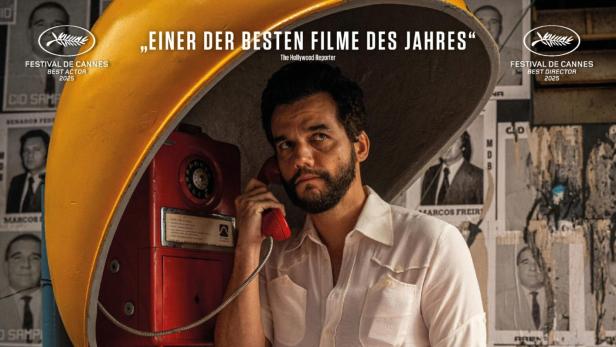 Mann telefoniert mit öffentlichem Telefon, während an der Wand im Hintergrund Fahnungsplakat zu sehen sind