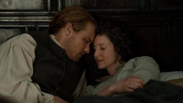 Mann und Frau in altertümlicher Kleidung legen ihre Köpfe aneinander