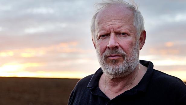 Graubärtiger Mann vor Horizont mit auf- oder untergehender Sonne