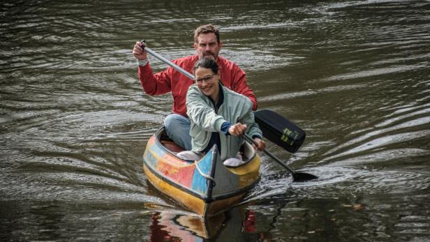 Mann und Frau sitzen in Boot und paddeln