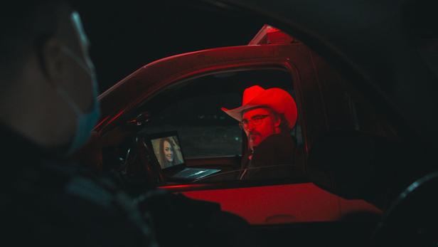 Joaquin Phoenix als Sheriff sitzt nachts in seinem Dienstwagen und wird durch einen Scheinwerfer in rotes Licht getaucht