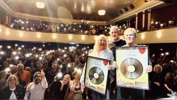 Schriftstellerin Rita Falk, Schauspieler Christian Tramitz und Moderator Florian Wagner auf Bühne eines vollen Theatersaales