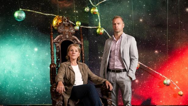 Sitzende Frau und stehender Mann in einem Raum, der wie ein Planetarium ausgestattet wurde