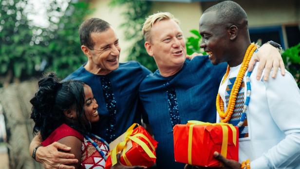 Kai Pflaume (2.v.l.) und Jens "Knossi" Knossalla umarmen ein Schwarzes Paar das Geschenke in Händen hält