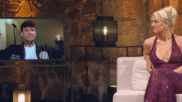 Frau auf Sofa sieht Mann per Videoschaltung auf Bildschirm