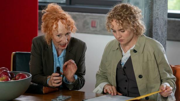 Zwei Frauen sitzen an einem Arbeitstisch und sprechen miteinander