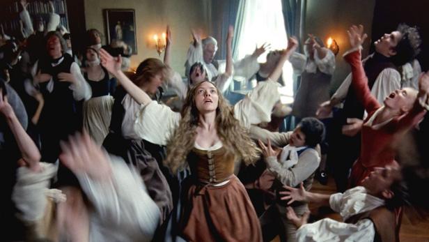 Amanda Seyfried tanzt in Filmrolle mit ausgebreiteten Armen inmitten einer Gruppe von Gleichgesinnten
