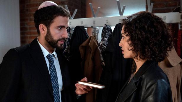 Mann übergibt Frau in einer Garderobe ein Notizbuch