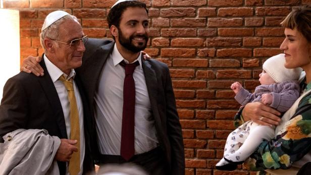 Zwei Männer stehen einer Frau mit Baby gegenüber